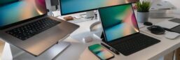 A contemporary workspace featuring a laptop, tablet, smartphone, and monitor displaying abstract backgrounds.